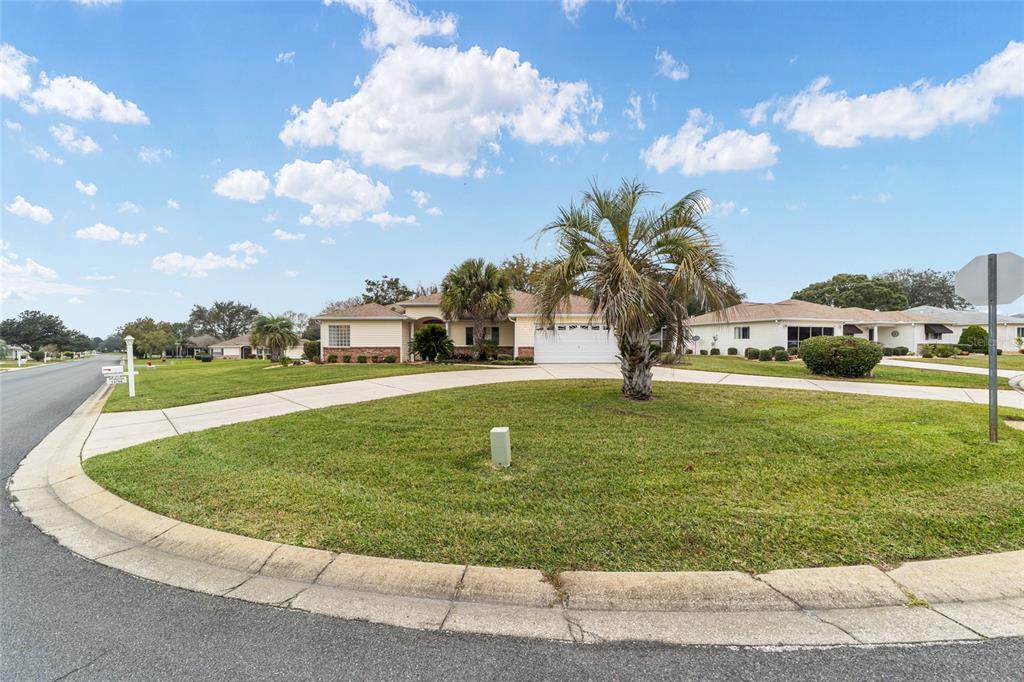 A single-story house with a two-car garage, light siding, and a large concrete driveway — 13766 SE 89TH AVENUE, SUMMERFIELD, FL