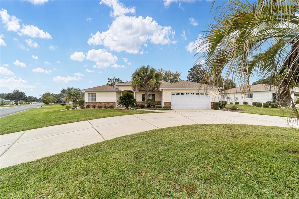 A single-story house with light siding, a brick accent, and a concrete driveway — 13766 SE 89TH AVENUE, SUMMERFIELD, FL