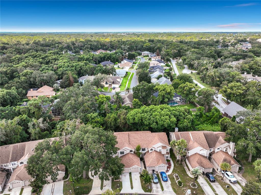 A two-story tan house with two garage doors and a concrete driveway under large trees — 635 NORTHBRIDGE DRIVE, ALTAMONTE SPRINGS, FL