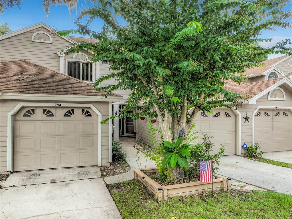An exterior view of a tan townhouse with a garage and a concrete walkway — 635 NORTHBRIDGE DRIVE, ALTAMONTE SPRINGS, FL