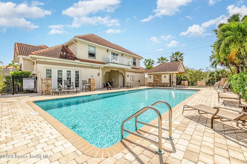 A swimming pool sits on a paved patio behind a two-story house with a balcony — 1800 KOLE PLACE, MELBOURNE, FL