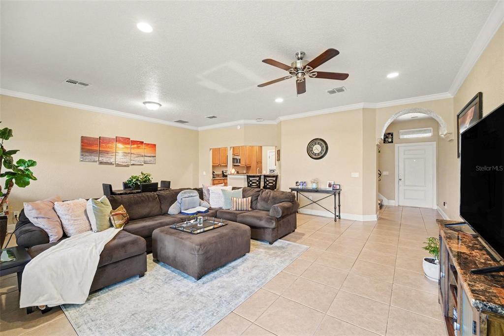 A living room features a large brown sectional sofa, tile flooring, and an open kitchen — 1800 KOLE PLACE, MELBOURNE, FL