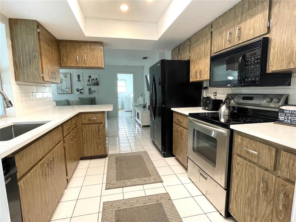 A kitchen with wood cabinets, white countertops, stainless steel appliances, and white tile flooring — 2908 CAPTIVA DRIVE, SARASOTA, FL