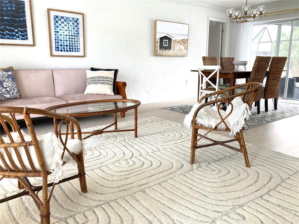 A living and dining area features a pink sofa, rattan chairs, and a textured rug — 2908 CAPTIVA DRIVE, SARASOTA, FL