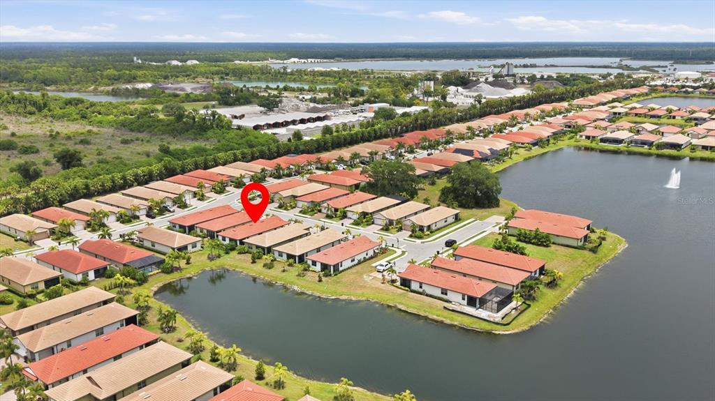 Aerial view of a residential neighborhood with houses surrounding a lake and a red marker — 113 MOSCATA WAY, NOKOMIS, FL