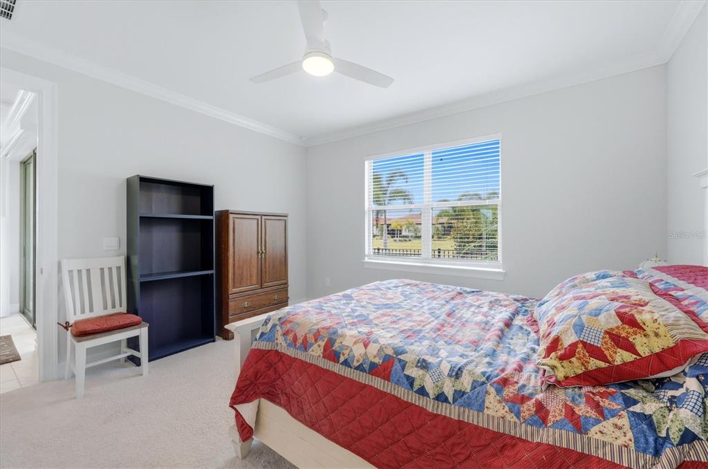 A bedroom features a bed with a colorful quilt, a wooden armoire, and a bookshelf — 113 MOSCATA WAY, NOKOMIS, FL