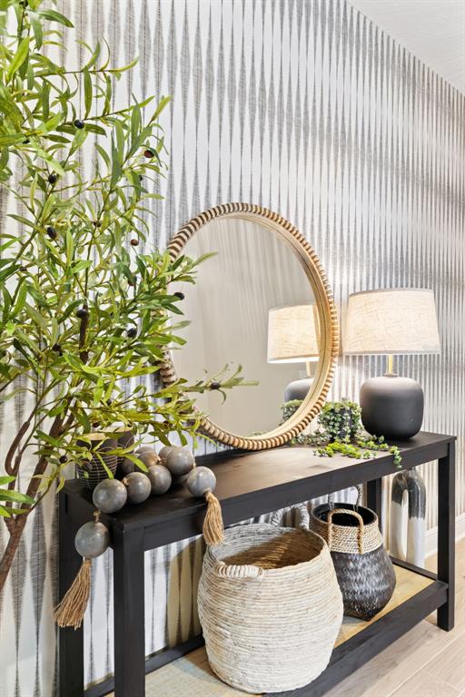 A black console table sits against a patterned wallpaper wall with a mirror and lamp — 3621 WILD BLOSSOM PLACE, PARRISH, FL