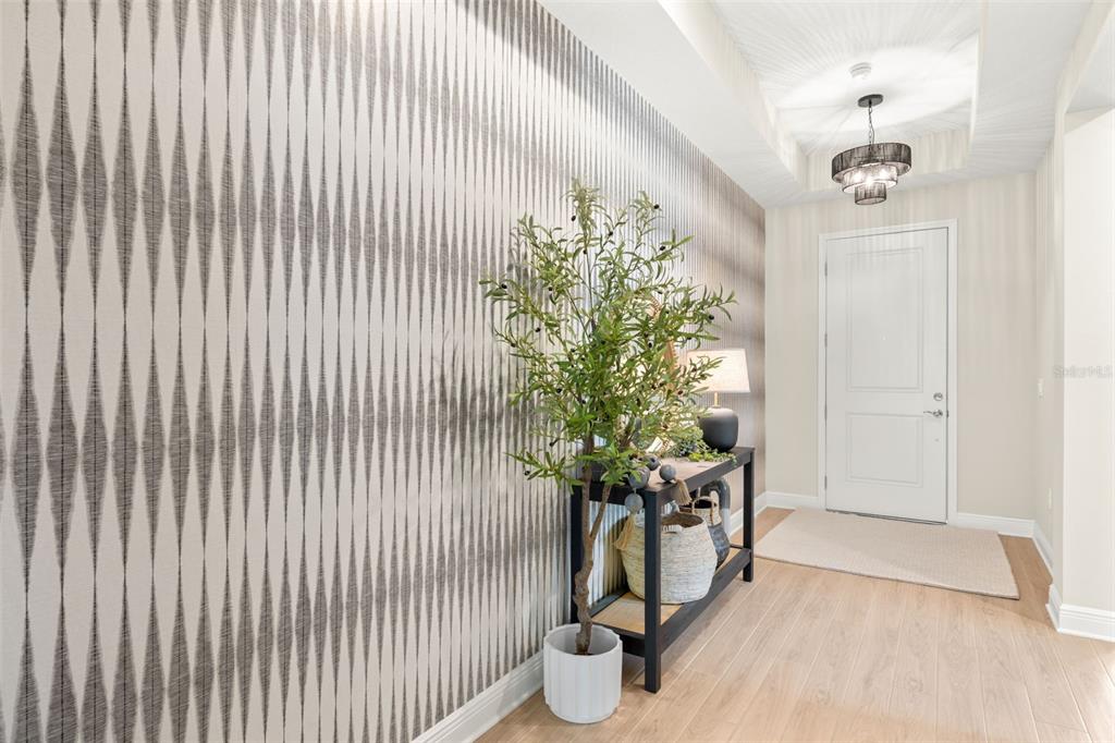 A foyer features patterned wallpaper, a console table with a potted plant, and a light fixture — 3621 WILD BLOSSOM PLACE, PARRISH, FL