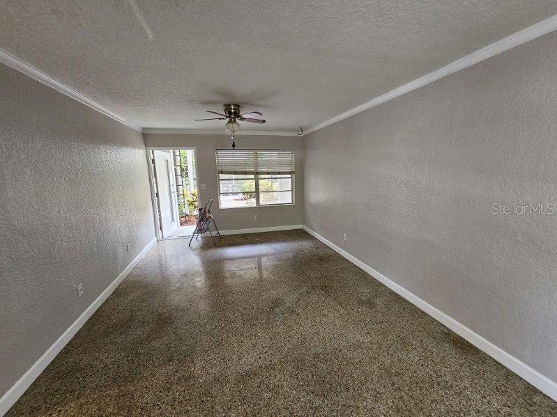 An empty living room features gray walls, white trim, a ceiling fan, and terrazzo flooring — 212 S CHURCH AVENUE UNIT 107, TAMPA, FL