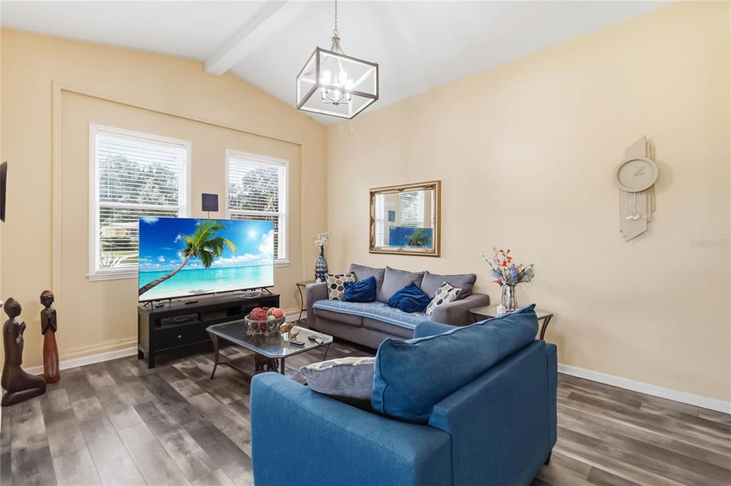 A living room features a blue sofa, a grey sofa, a television, and wood-look flooring — 841 WOODEN BOULEVARD, ORLANDO, FL