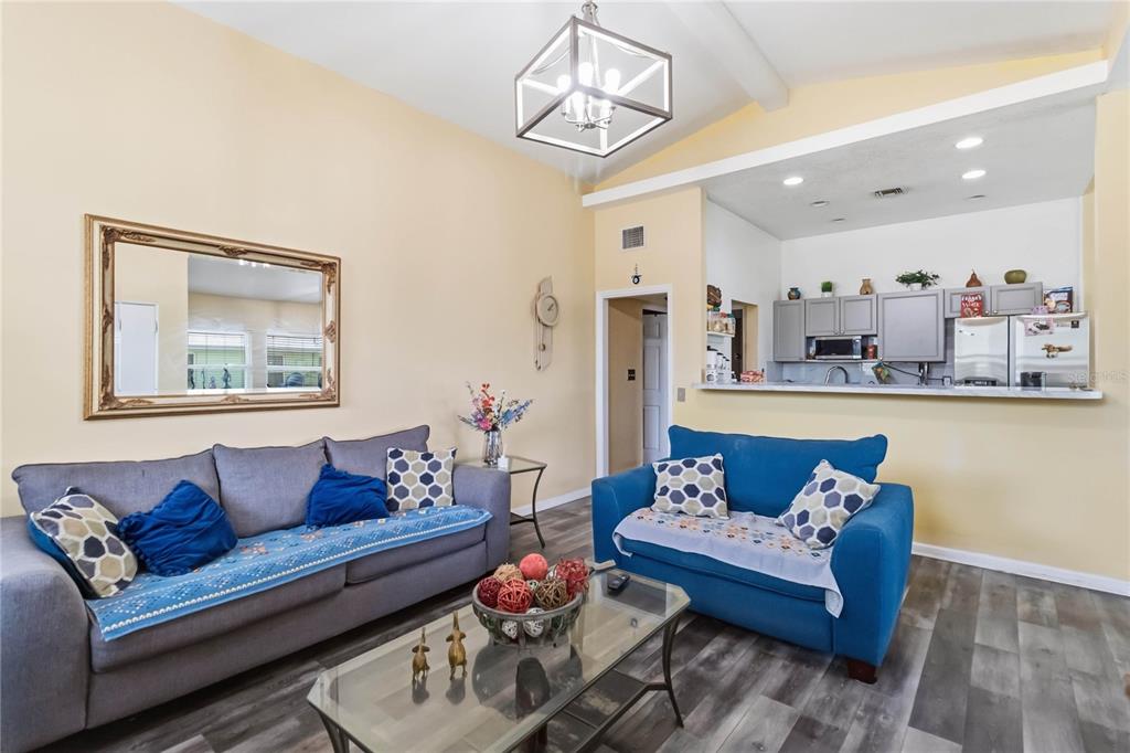 A living room with two sofas, a glass coffee table, and an open kitchen area — 841 WOODEN BOULEVARD, ORLANDO, FL
