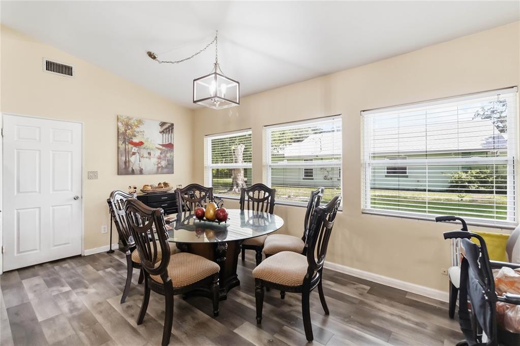 A dining room features a glass-topped table, six chairs, wood-look flooring, and three large windows — 841 WOODEN BOULEVARD, ORLANDO, FL