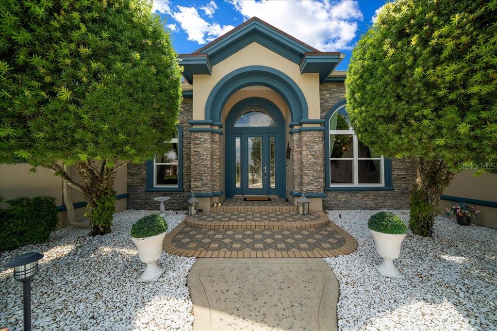 The front entrance of a house features a stone facade, blue trim, and arched doorway — 3970 SE 39TH CIRCLE, OCALA, FL