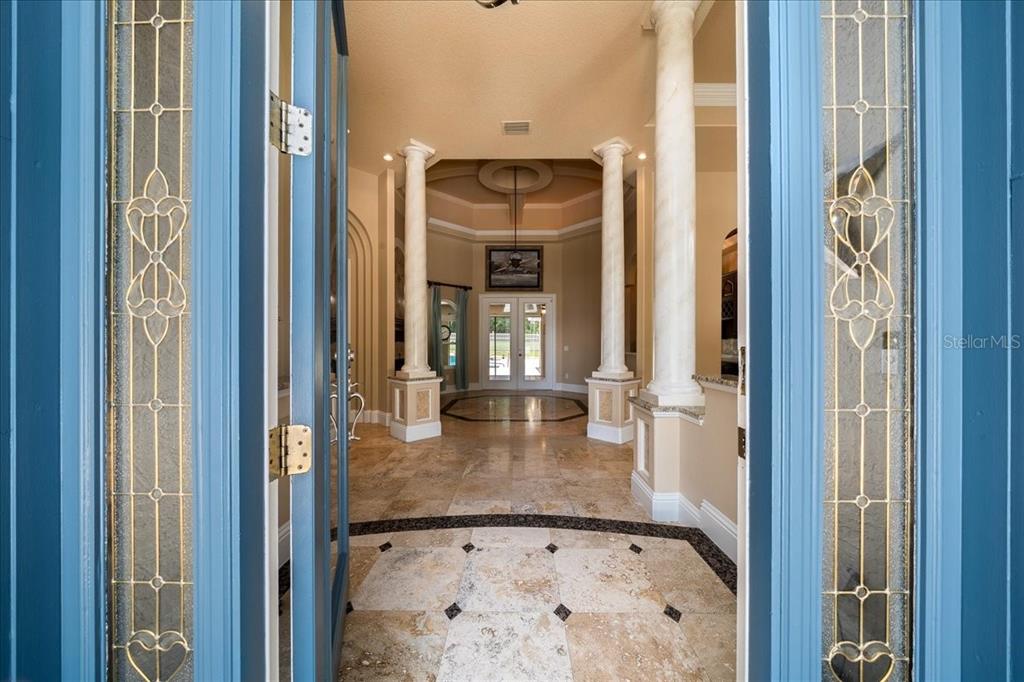 A view through an open blue door into a foyer with columns and tile flooring — 3970 SE 39TH CIRCLE, OCALA, FL