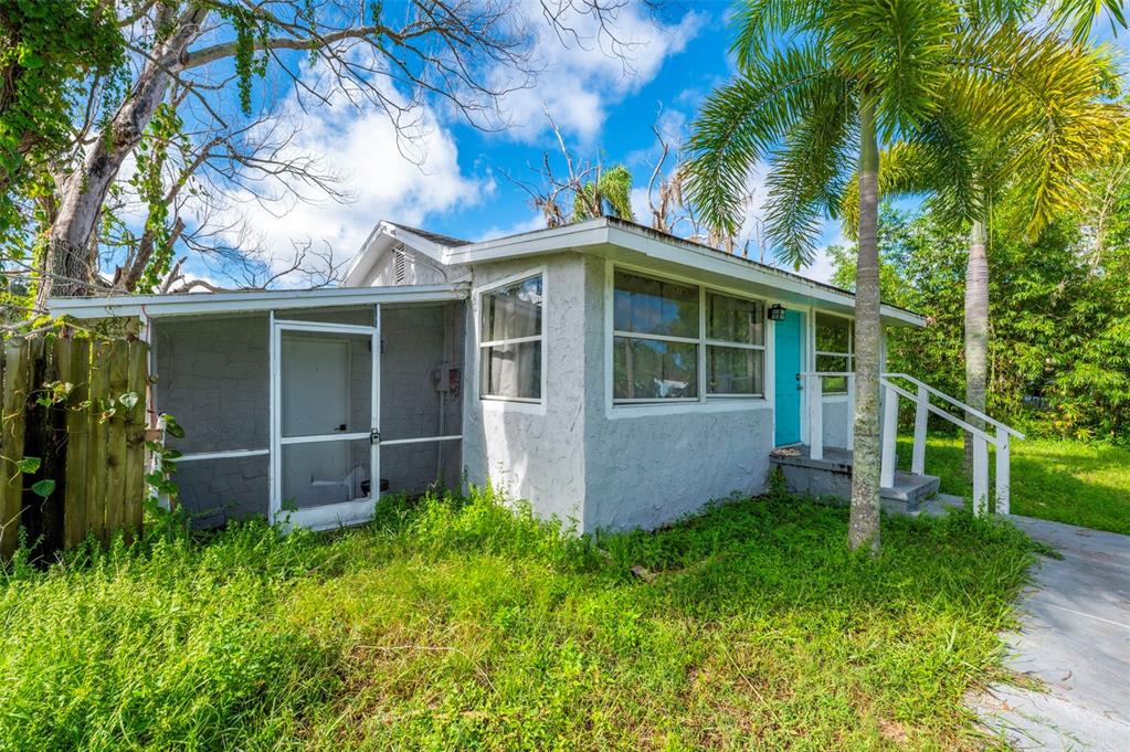 A small, single-story gray house with a screened-in porch and overgrown grass in the yard — 5200 MALLETT DRIVE, PORT RICHEY, FL