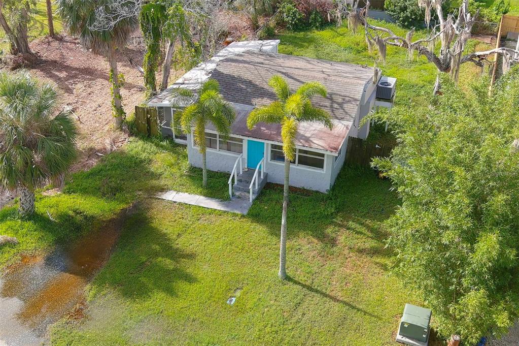 An aerial view of a small, single-story house with a bright blue door and palm trees — 5200 MALLETT DRIVE, PORT RICHEY, FL