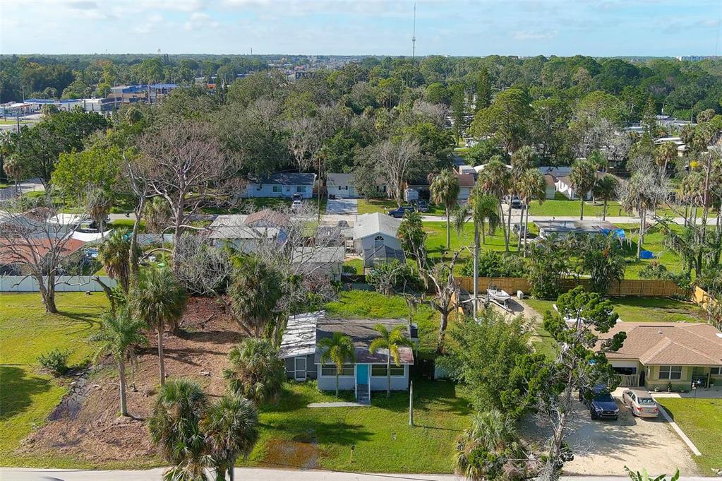 An aerial view shows a single-story house with a blue door surrounded by green lawns — 5200 MALLETT DRIVE, PORT RICHEY, FL