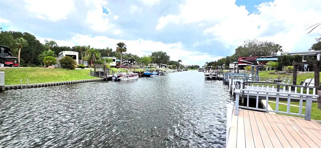 A canal view shows boats docked alongside recreational vehicles and grassy waterfront properties — 568 WATERWAY DRIVE, RIVER RANCH, FL