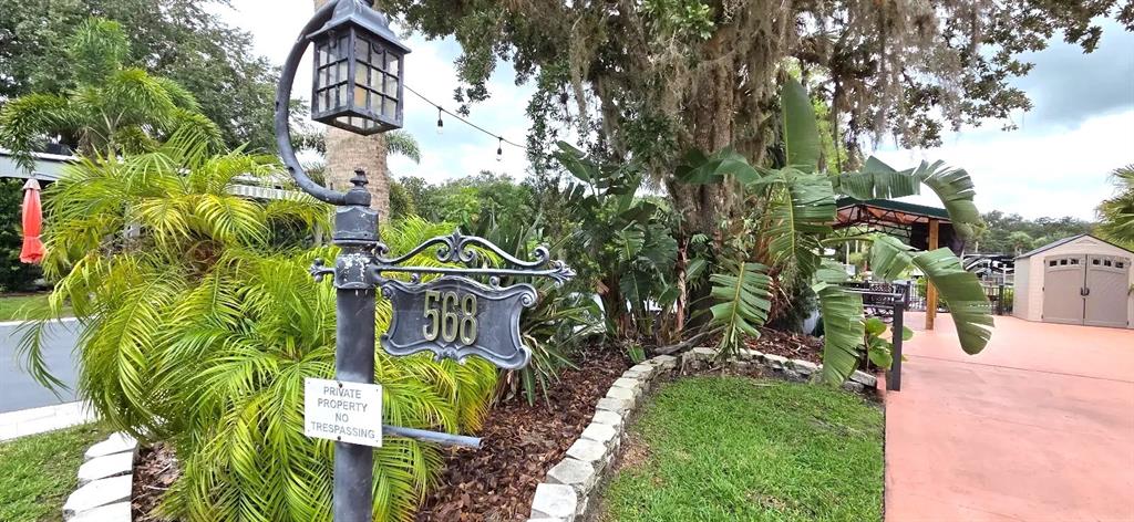 A decorative lamp post with a house number sign stands in a landscaped yard — 568 WATERWAY DRIVE, RIVER RANCH, FL