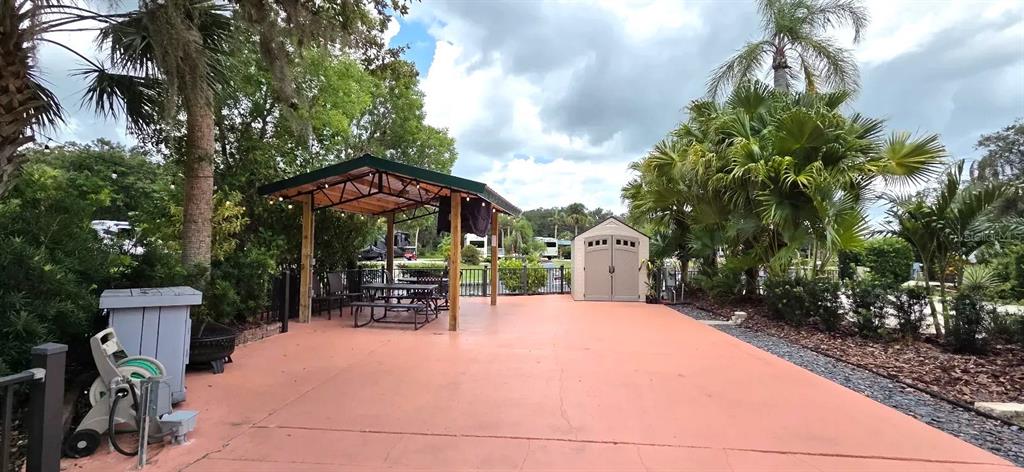 An outdoor patio features a covered dining area, a storage shed, and tropical landscaping — 568 WATERWAY DRIVE, RIVER RANCH, FL