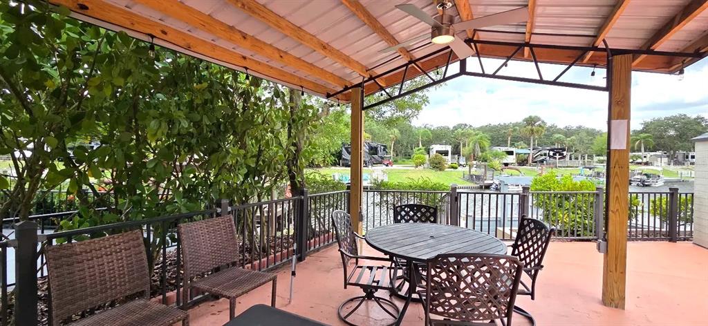 A covered outdoor patio features a dining set, ceiling fan, and views of a canal — 568 WATERWAY DRIVE, RIVER RANCH, FL
