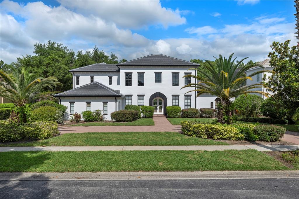 A two-story white house with a dark roof, arched entryway, and palm trees in the yard — 10849 EMERALD CHASE DRIVE, ORLANDO, FL