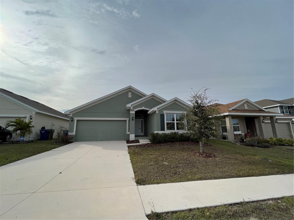 A single-story house with a green exterior, a two-car garage, and a concrete driveway — 136 KRENSON BAY LOOP, WINTER HAVEN, FL
