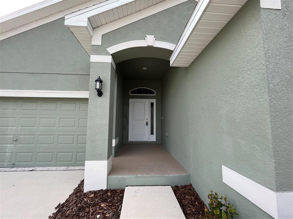 A sage green house exterior features a white front door, a garage, and a walkway — 136 KRENSON BAY LOOP, WINTER HAVEN, FL