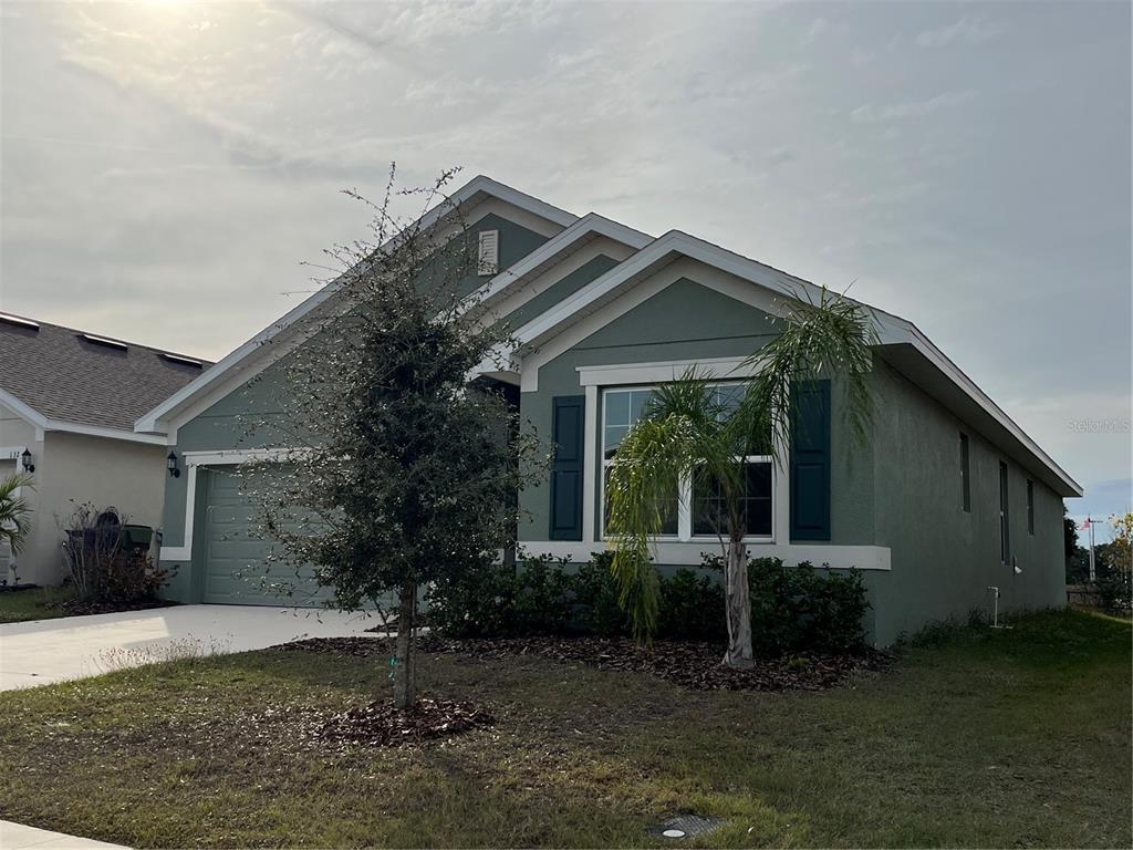A single-story green house with a two-car garage and a small palm tree — 136 KRENSON BAY LOOP, WINTER HAVEN, FL