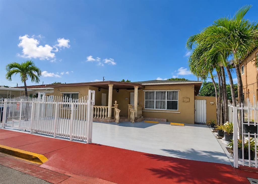 A single-story house with a tan exterior, a covered porch, and a white metal fence — 955 79TH TERRACE, MIAMI BEACH, FL