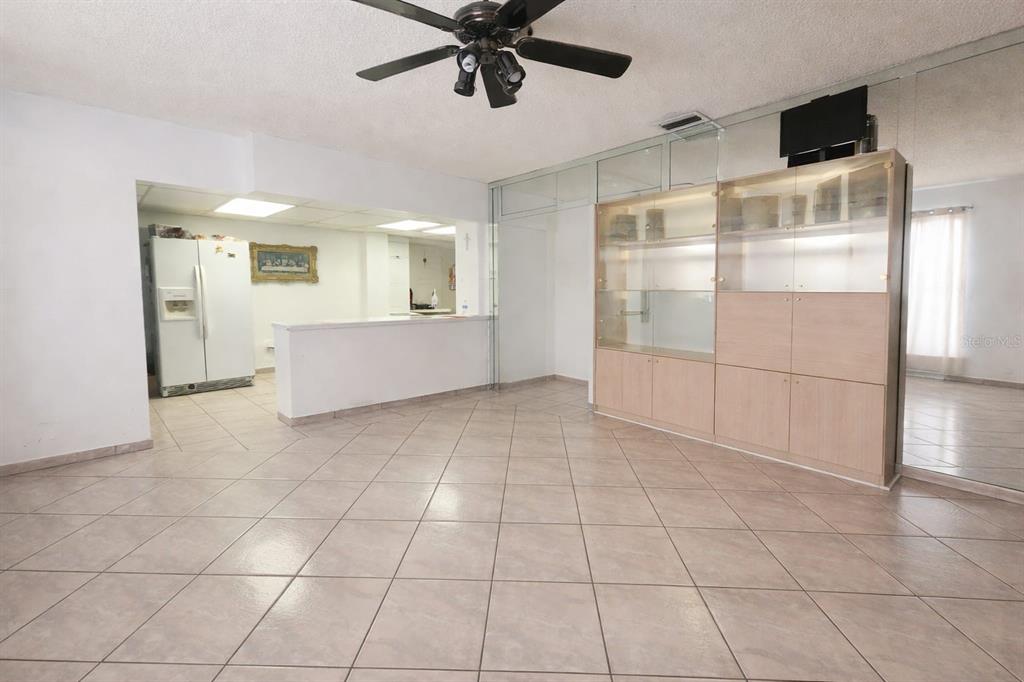 A room with light-colored tile flooring, a ceiling fan, a kitchen pass-through, and cabinetry — 955 79TH TERRACE, MIAMI BEACH, FL