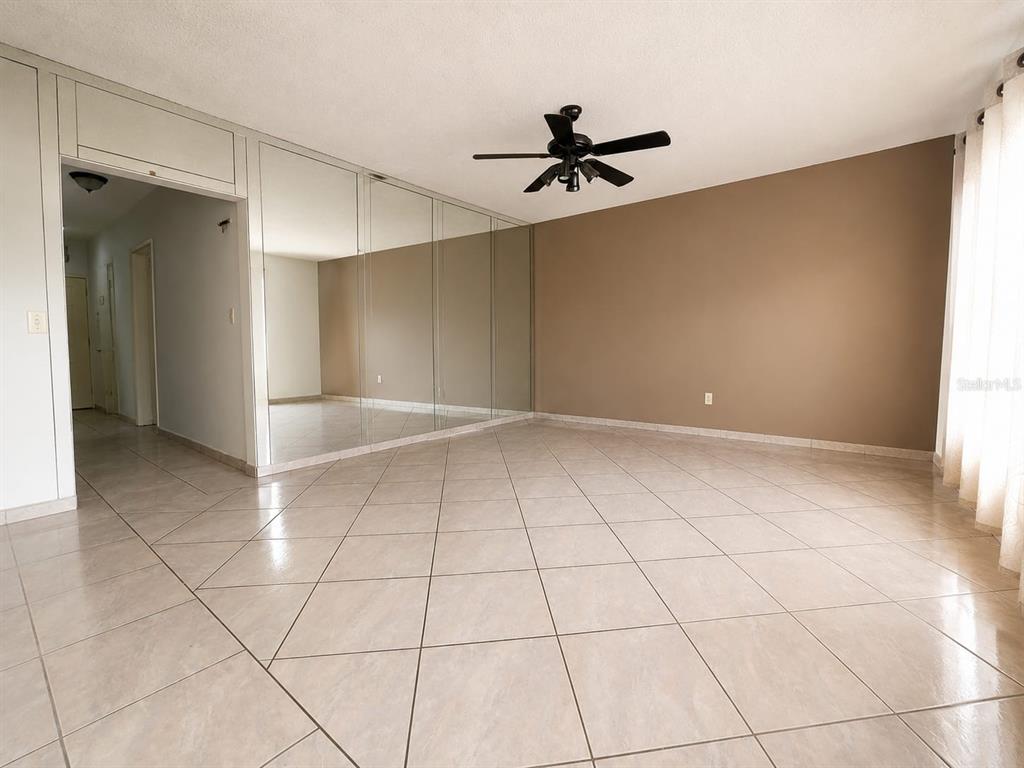 A living room features beige tile flooring, a mirrored wall, and a ceiling fan — 955 79TH TERRACE, MIAMI BEACH, FL