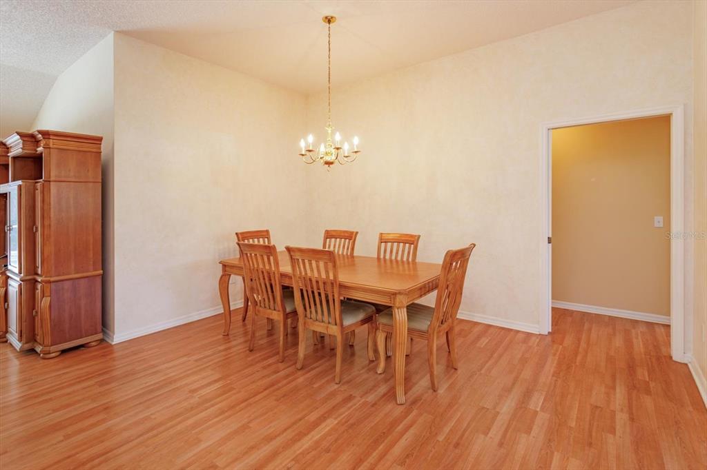 A dining room with a wooden table, six chairs, a chandelier, and light-colored walls — 1115 SALDIVAR ROAD, THE VILLAGES, FL