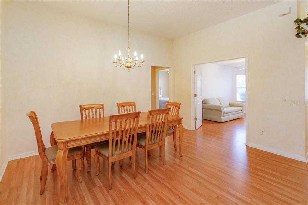 A dining room features a wooden table, six chairs, a chandelier, and light-colored walls — 1115 SALDIVAR ROAD, THE VILLAGES, FL