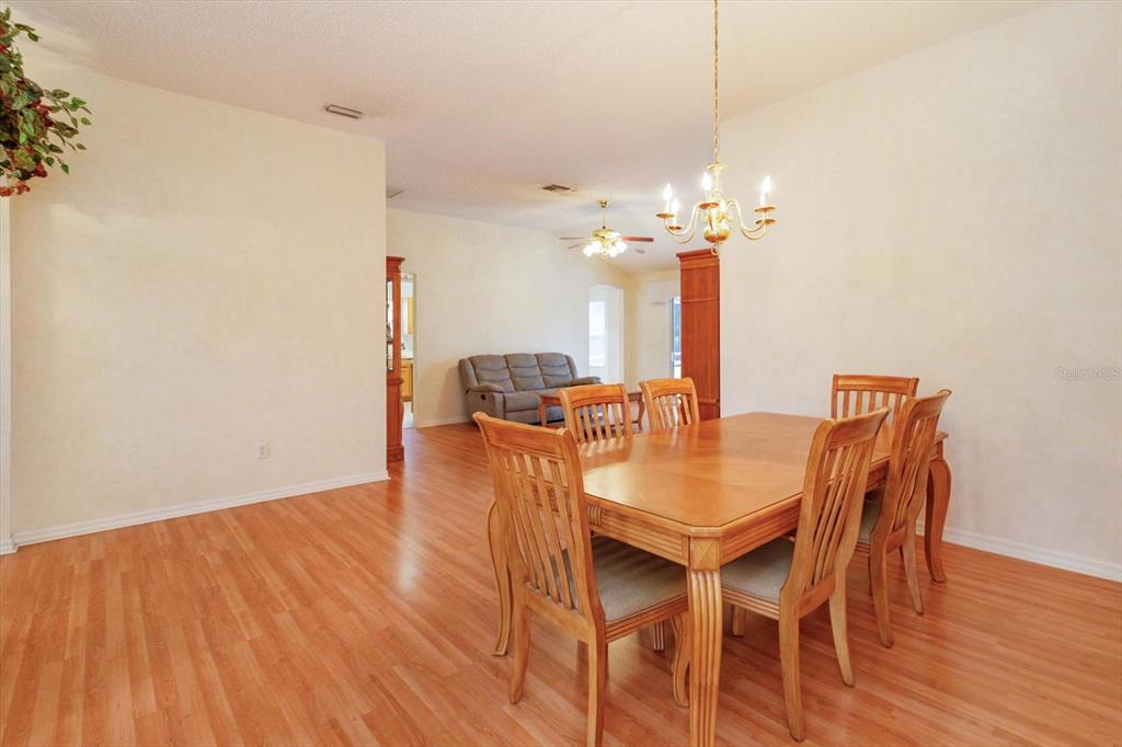 A dining room with a wooden table and chairs sits adjacent to a living area — 1115 SALDIVAR ROAD, THE VILLAGES, FL