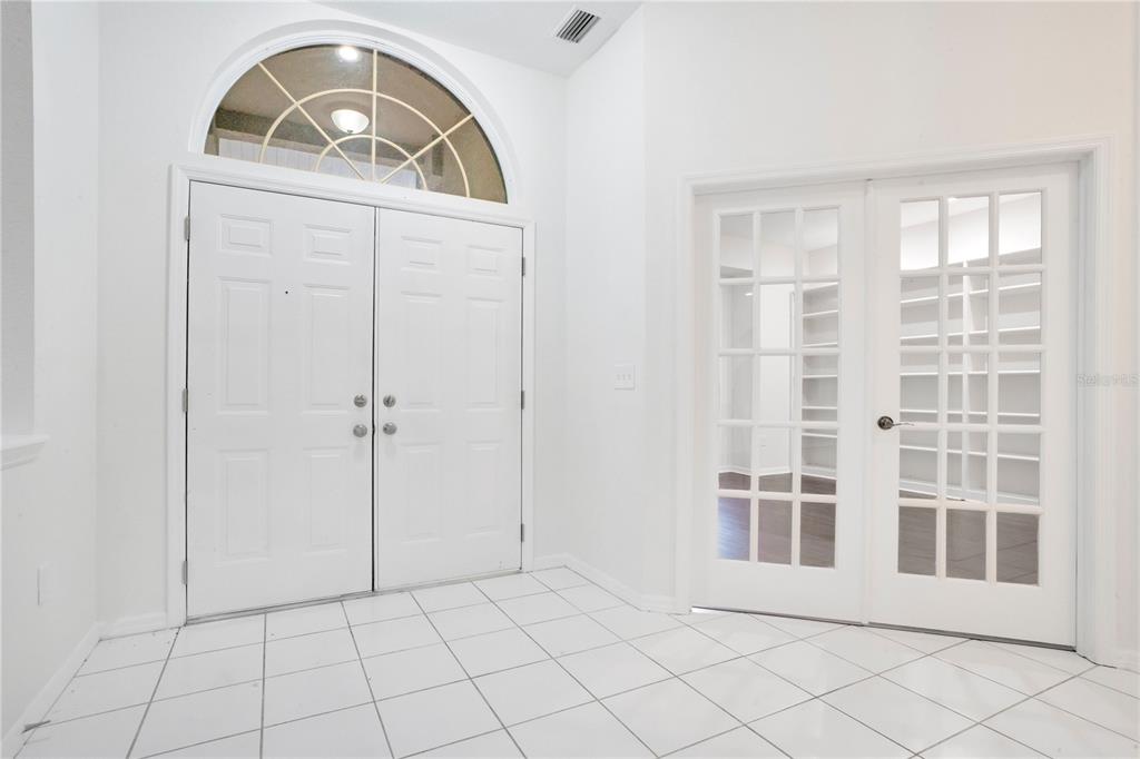 An entryway features white tile flooring, double front doors with an arched window, and French doors — 3404 RIVER WOODS DRIVE, PARRISH, FL