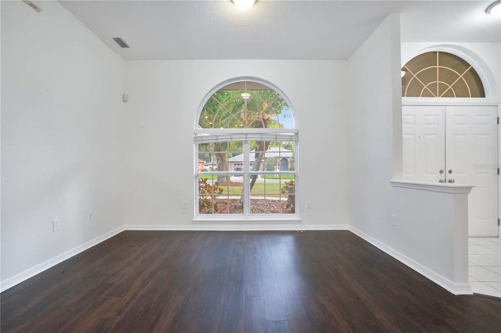An empty room with dark wood flooring, white walls, and a large arched window — 3404 RIVER WOODS DRIVE, PARRISH, FL