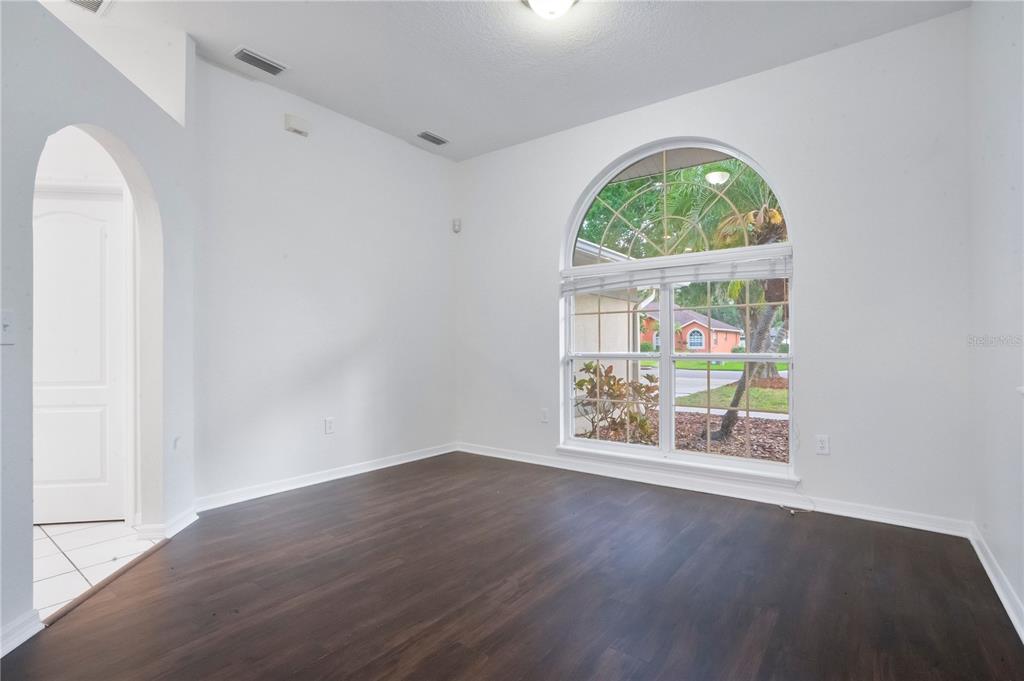 An empty room with dark wood flooring, white walls, and a large arched window — 3404 RIVER WOODS DRIVE, PARRISH, FL