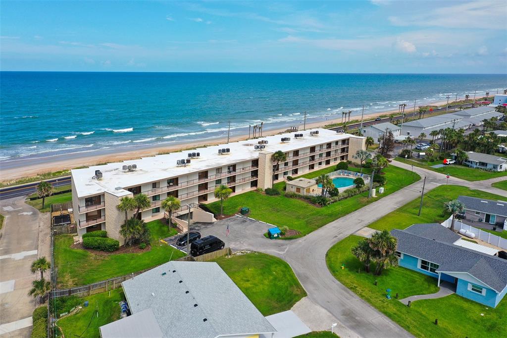An aerial view shows a multi-story apartment building with a pool located near the ocean — 2600 OCEAN SHORE BOULEVARD UNIT 111, ORMOND BEACH, FL