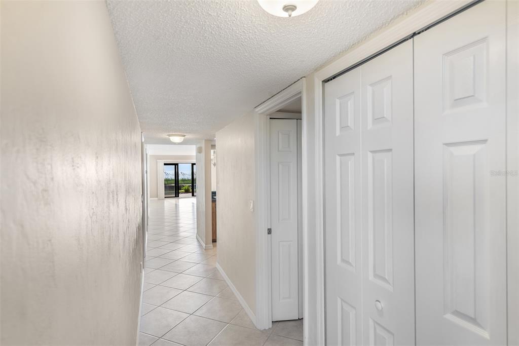 A hallway with tiled floors leads toward a bright living area with a sliding door — 2600 OCEAN SHORE BOULEVARD UNIT 111, ORMOND BEACH, FL