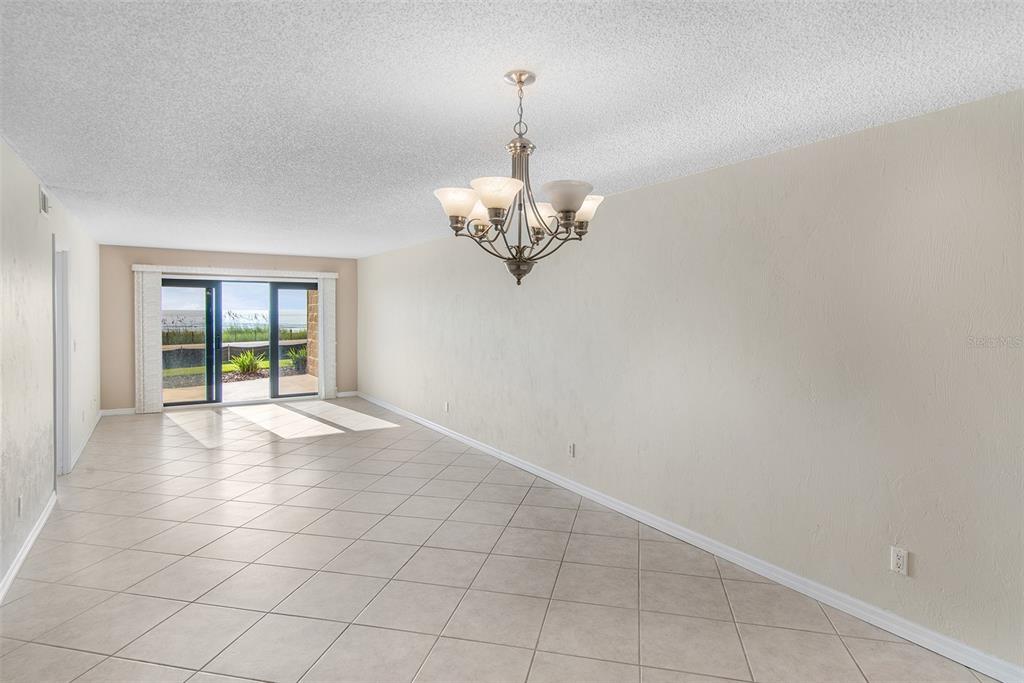 A dining room with tile flooring, a chandelier, and a sliding glass door to outside — 2600 OCEAN SHORE BOULEVARD UNIT 111, ORMOND BEACH, FL