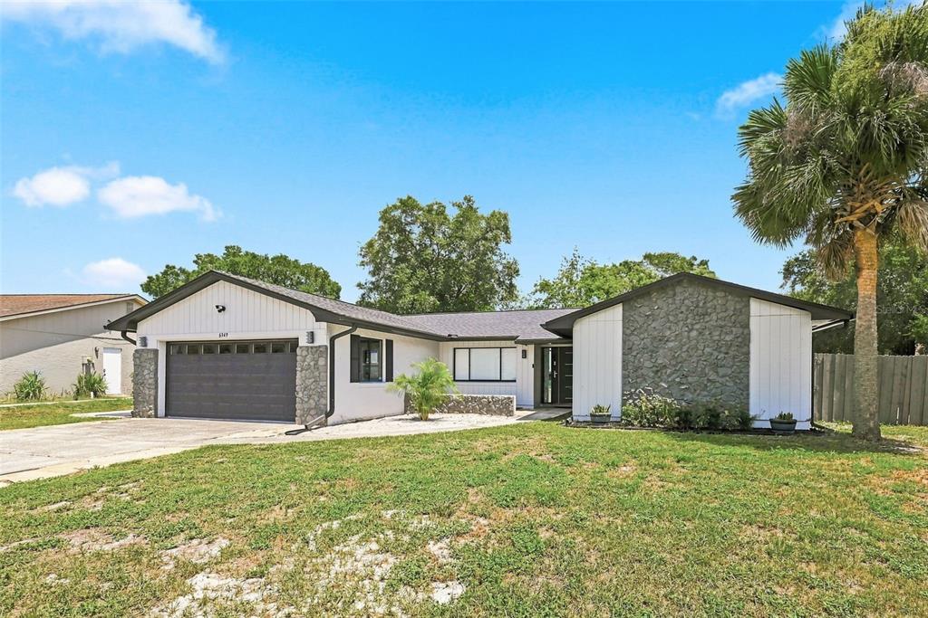 A single-story house with a stone facade, white siding, and a two-car garage — 6349 MARLBERRY DRIVE, ORLANDO, FL
