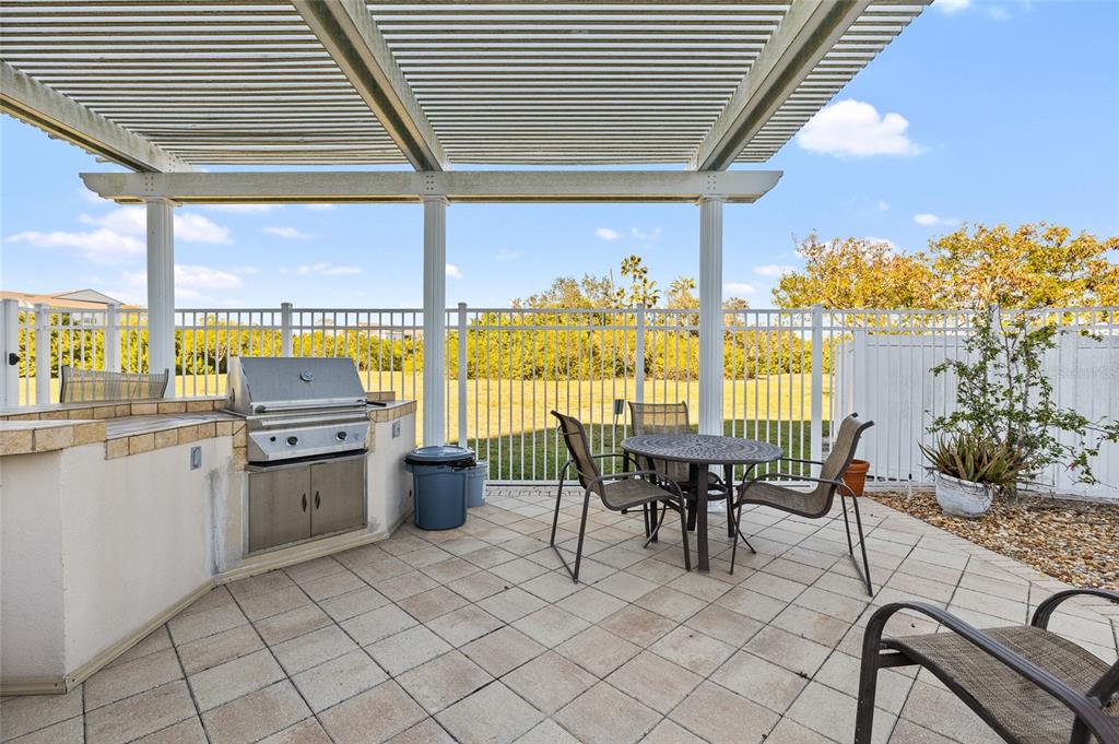 A patio features a built-in grill, a dining set, and a pergola under a sky — 10851 MANGROVE CAY LANE NE UNIT 1112, ST PETERSBURG, FL