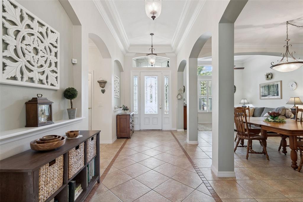 A tiled entryway features arched openings, a decorative wall panel, and a view into the dining — 106 OAK HAVEN CIRCLE, DELAND, FL