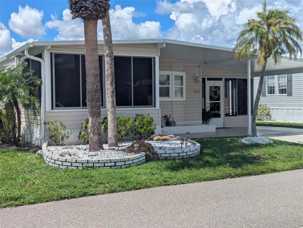 A single-story mobile home features a carport, a landscaped front garden, and palm trees — 2100 KINGS HIGHWAY UNIT 137, PORT CHARLOTTE, FL