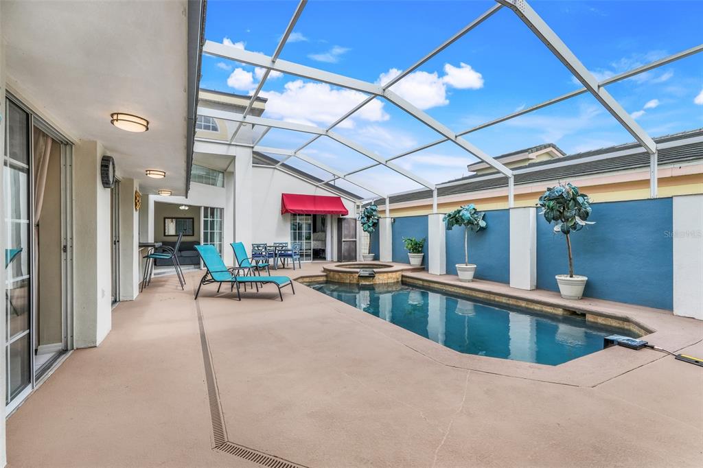 A screened-in patio features a swimming pool, a hot tub, and blue accent walls — 8807 CRAYSON COURT, KISSIMMEE, FL