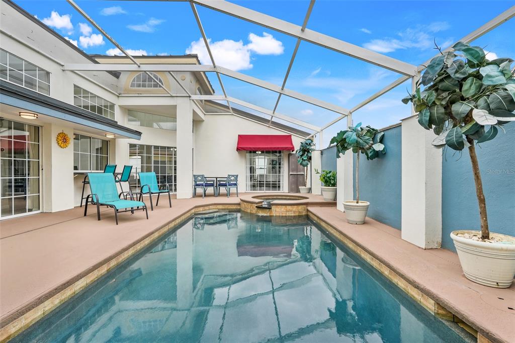 A screened-in patio features a rectangular swimming pool, a raised spa, and lounge chairs — 8807 CRAYSON COURT, KISSIMMEE, FL