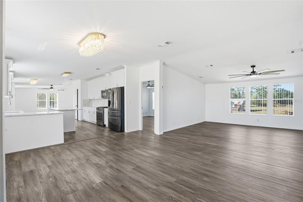 An open-concept living area features wood-look flooring, white walls, and a modern kitchen — 3844 KAISER AVENUE, ST CLOUD, FL
