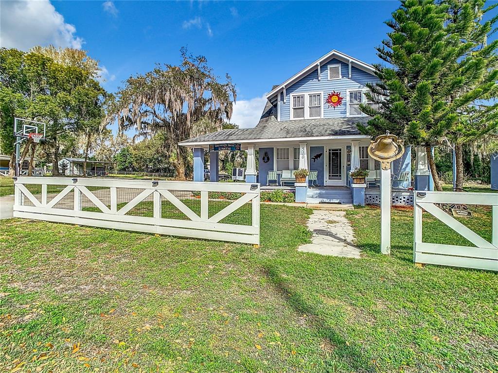 A blue two-story house with a front porch and white fence sits on a lawn — 510 TIGHE AVENUE, SEFFNER, FL