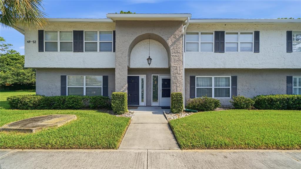 A two-story apartment building exterior features a central arched entryway and a concrete walkway — 695 A1A N UNIT 50, PONTE VEDRA BEACH, FL